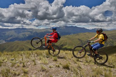 Peru, Cusco 'da antik dağlık patikalar boyunca seyahat eden bir grup dağ bisikletçisi, otantik yerel kültür, tarihi manzaralar ve uzak bir And ortamında aktif bir yaşam tarzı ve keşif ruhunu yansıtan açık hava maceraları yaşıyorlar..