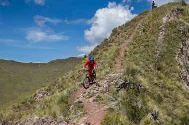 Peru, Cusco 'da antik dağlık patikalar boyunca seyahat eden bir grup dağ bisikletçisi, otantik yerel kültür, tarihi manzaralar ve uzak bir And ortamında aktif bir yaşam tarzı ve keşif ruhunu yansıtan açık hava maceraları yaşıyorlar..