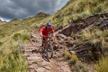 Peru, Cusco 'da antik dağlık patikalar boyunca seyahat eden bir grup dağ bisikletçisi, otantik yerel kültür, tarihi manzaralar ve uzak bir And ortamında aktif bir yaşam tarzı ve keşif ruhunu yansıtan açık hava maceraları yaşıyorlar..