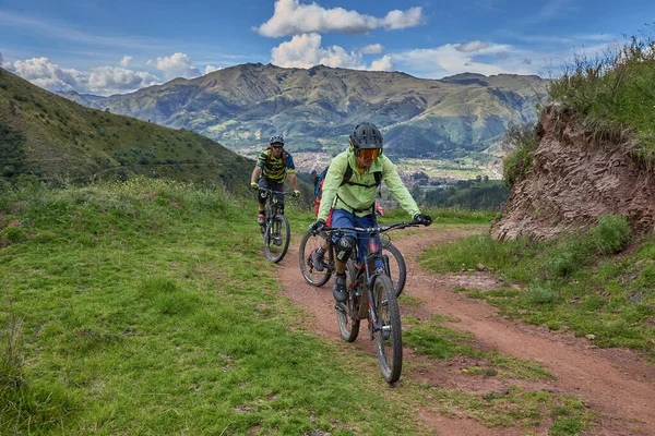 Peru, Cusco 'da antik dağlık patikalar boyunca seyahat eden bir grup dağ bisikletçisi, otantik yerel kültür, tarihi manzaralar ve uzak bir And ortamında aktif bir yaşam tarzı ve keşif ruhunu yansıtan açık hava maceraları yaşıyorlar..