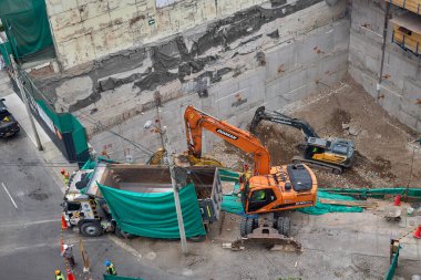 Miraflores 'te büyük bir inşaat sahasında faaliyet gösteren kazıcılar, büyüyen bir şehir ortamında güvenli çalışma uygulamaları, modern inşaat standartları ve kentsel emlak gelişimini gösteriyorlar..