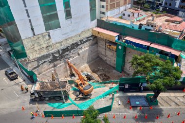 Miraflores 'te büyük bir inşaat sahasında faaliyet gösteren kazıcılar, büyüyen bir şehir ortamında güvenli çalışma uygulamaları, modern inşaat standartları ve kentsel emlak gelişimini gösteriyorlar..