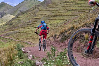 Peru, Cusco 'da antik dağlık patikalar boyunca seyahat eden bir grup dağ bisikletçisi, otantik yerel kültür, tarihi manzaralar ve uzak bir And ortamında aktif bir yaşam tarzı ve keşif ruhunu yansıtan açık hava maceraları yaşıyorlar..