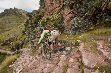 Peru, Cusco 'da antik dağlık patikalar boyunca seyahat eden bir grup dağ bisikletçisi, otantik yerel kültür, tarihi manzaralar ve uzak bir And ortamında aktif bir yaşam tarzı ve keşif ruhunu yansıtan açık hava maceraları yaşıyorlar..