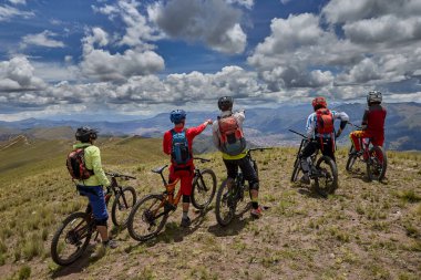 Peru, Cusco 'da antik dağlık patikalar boyunca seyahat eden bir grup dağ bisikletçisi, otantik yerel kültür, tarihi manzaralar ve uzak bir And ortamında aktif bir yaşam tarzı ve keşif ruhunu yansıtan açık hava maceraları yaşıyorlar..