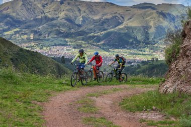 Peru, Cusco 'da antik dağlık patikalar boyunca seyahat eden bir grup dağ bisikletçisi, otantik yerel kültür, tarihi manzaralar ve uzak bir And ortamında aktif bir yaşam tarzı ve keşif ruhunu yansıtan açık hava maceraları yaşıyorlar..
