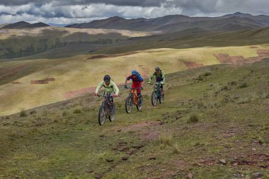 Peru, Cusco 'da antik dağlık patikalar boyunca seyahat eden bir grup dağ bisikletçisi, otantik yerel kültür, tarihi manzaralar ve uzak bir And ortamında aktif bir yaşam tarzı ve keşif ruhunu yansıtan açık hava maceraları yaşıyorlar..
