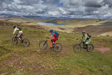 Peru, Cusco 'da antik dağlık patikalar boyunca seyahat eden bir grup dağ bisikletçisi, otantik yerel kültür, tarihi manzaralar ve uzak bir And ortamında aktif bir yaşam tarzı ve keşif ruhunu yansıtan açık hava maceraları yaşıyorlar..