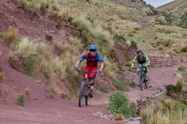 Peru, Cusco 'da antik dağlık patikalar boyunca seyahat eden bir grup dağ bisikletçisi, otantik yerel kültür, tarihi manzaralar ve uzak bir And ortamında aktif bir yaşam tarzı ve keşif ruhunu yansıtan açık hava maceraları yaşıyorlar..