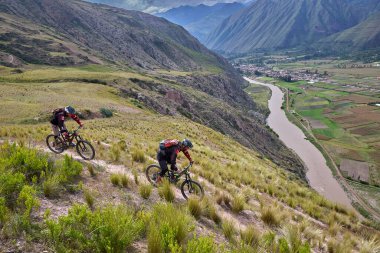 Peru, Cusco 'da antik dağlık patikalar boyunca seyahat eden bir grup dağ bisikletçisi, otantik yerel kültür, tarihi manzaralar ve uzak bir And ortamında aktif bir yaşam tarzı ve keşif ruhunu yansıtan açık hava maceraları yaşıyorlar..