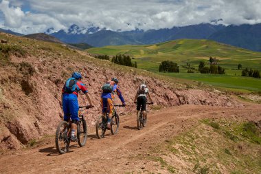 Peru, Cusco 'da antik dağlık patikalar boyunca seyahat eden bir grup dağ bisikletçisi, otantik yerel kültür, tarihi manzaralar ve uzak bir And ortamında aktif bir yaşam tarzı ve keşif ruhunu yansıtan açık hava maceraları yaşıyorlar..