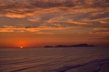 Pasifik Okyanusu üzerinde canlı bir yaz günbatımı Limas Costa Verde boyunca, ufukta San Lorenzo Adası silueti ile. Sıcak altın ışık dalgaların arasından yansıyarak, gevşek kıyı atmosferini ve aktif sahil yaşam tarzını yakalar.