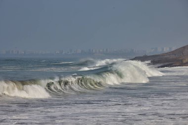 Güçlü bir Pasifik dalgası, doğanın ham güzelliğini ve Perus 'un canlı kıyı manzarası boyunca gezginler ve turistler için ilham verici dinamik deniz çevresini gözler önüne sererek Lima' nın sahil şeridine akmaktadır..