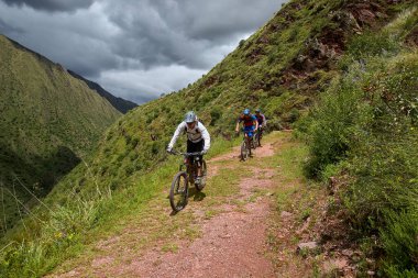 Peru 'nun kutsal vadisi Cusco' da sınırlarını Andean manzaraları ve antik tarım arazileriyle çevreleyen dağ bisikletçileri zorluyor. Bu dinamik açık hava sahnesi macera seyahatini yakalar.,