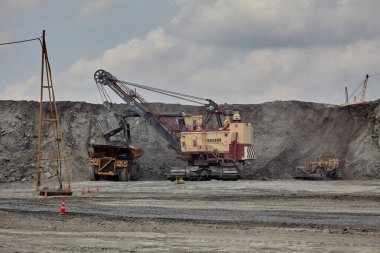 Büyük elektrikli halat küreği, açık kömür madenine ultra-sınıf bir maden kamyonu yüklüyor. Bu da yükleme döngüleri, ekipman konumlandırmaları ve kontrollü malzeme taşımacılığında en iyi uygulamaları gösteriyor..