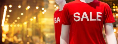 Manken, alışveriş merkezinin perakende sektöründe kırmızı t-shirt 'ün üzerine satış mektubu takıyor.