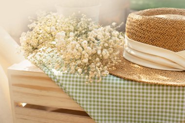 Beyaz çiçekli bej kadın şapkası ve açık hava aktivitesi için yeşil kumaş piknik örtüsü. 