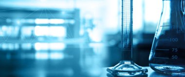 Tıp bilimi labaratuvarının mavi pankartında cam matara ve silindir.