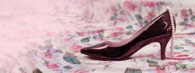 Kahverengi kadın yüksek topuklu ayakkabı ve pembe çiçek kumaşının arka planında inci ihmalkarlığı   