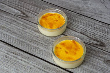 Tahta masaya kaşık konmuş Creme brulee. Fransa 'da meşhur, İspanyol Crema Catalana' sı gibi lezzetli bir tatlı. .