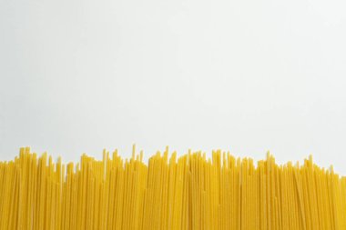 İtalyan makarna spagettisi pişirilmemiş, beyaz arka planda izole edilmiş. Yaratıcı sağlıklı gıda konsepti. Çiğ gıda arka planı oluşturun..