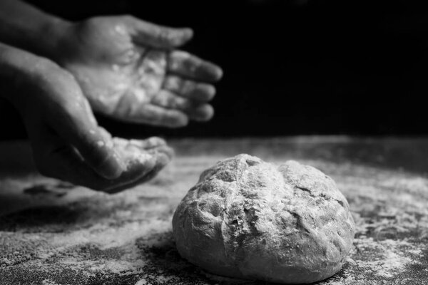 Концепция выпечки хлеба. Руки с мукой и традиционным хлебом на цветной столе.Черно-белое изображение с копировальным пространством.