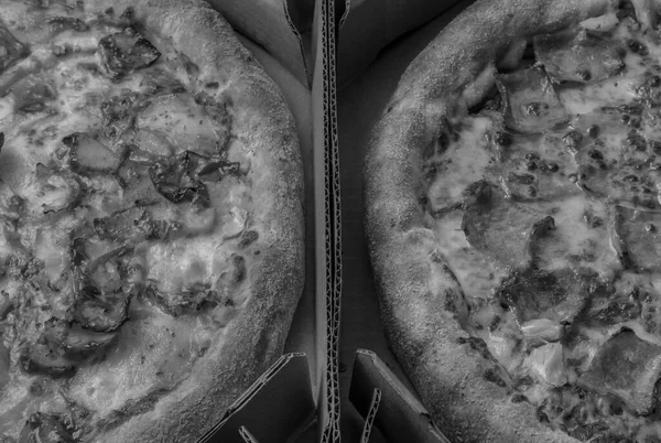 Closeup view of two pizzas on cardboard boxes.Top view of Hawaiian and Carbonara pizza with cheese, caramelized onion and bacon.Black and white style , restaurant promotional background concept.