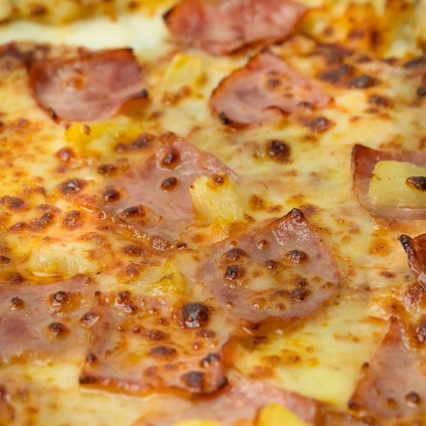 チーズ入りのおいしいハワイアンピザ 木製のピザボード上のクリスピーなベーコンとパイナップルと白い背景のクローズアップビュー — ストック写真