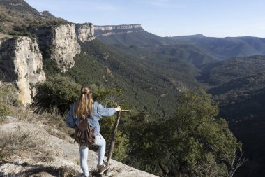 Bir ağaç dalı tutarken küçük sırt çantalı, dağlara bakan sarışın bir kadının portresi. Özgürlük seyahati, Rupit, Barselona, İspanya yakınlarındaki yaşam tarzı kavramını keşfetmek.