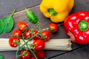 Kırsal ahşap masa üzerinde spagetti makarna ile taze sebzelerin üst görüntüsü. Sağlıklı İtalyan yemeği renkli bir kavram..