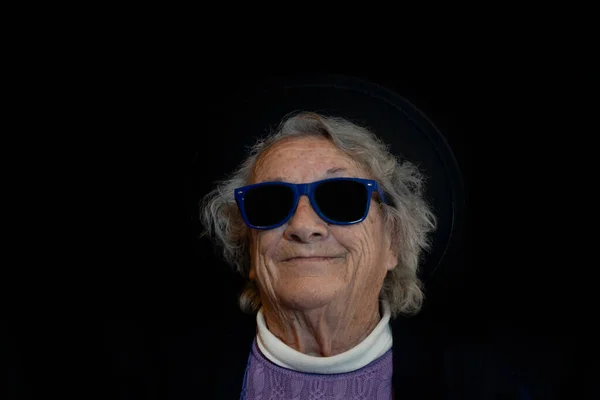 Senior elderly 80s woman with sunglasses on dark background.Portrait old people having fun ,studio lifestyle concept.