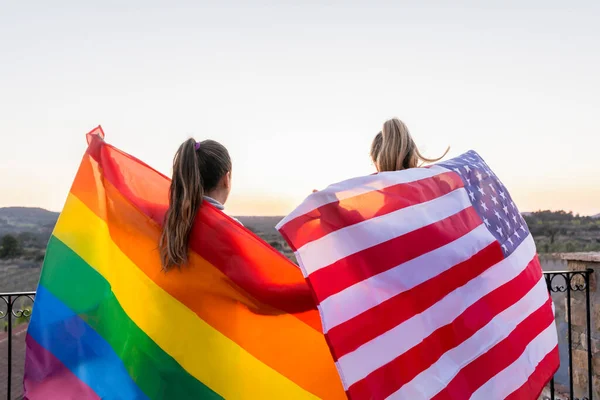 在夕阳西下拿着Lgtb彩虹旗和美国国旗的一对无法辨认的女同性恋者 美国和同性恋骄傲旗的概念生活方式 — 图库照片