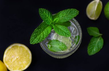 Yeşil taze limon, limon ve koyu arkaplanda naneli mojito kokteylinin en iyi görüntüsü.