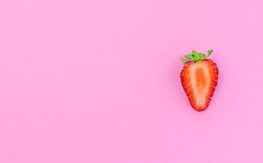Pembe pastel arka planda yarım çilek izole edilmiş. Minimum düz katman. Fotokopi alanı ile enfes sağlıklı gıda kavramı..