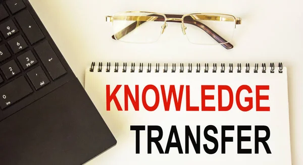 KNOWLEDGE TRANSFER, words on white notepad, near laptop and glasses .Business concept