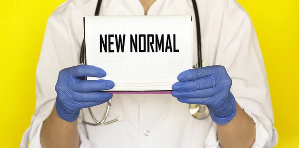 The doctor is holding a notebook with the text New Normal. Medicine concept