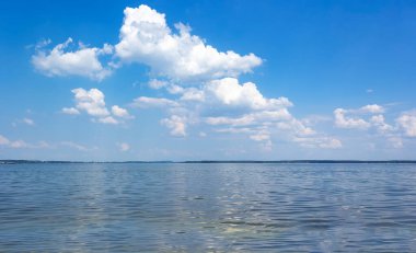 Mavi gökyüzü ve beyaz bulutlarla gölde yaz sıcağı