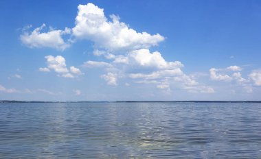 Mavi gökyüzü ve beyaz bulutlarla gölde yaz sıcağı