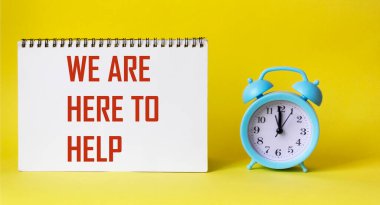 Sarı arka planda bir çalar saatin yanında bir not defterine yardım etmek için buradayız.