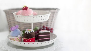 Çok renkli pastaları olan bir vazo beyaz arka planda duruyor. Yazacak bir yer var.