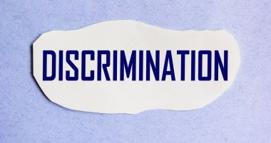 Ayrımcılık kelimesi mavi arka planda duran bir kağıt parçasına yazılmıştır. Kavram.