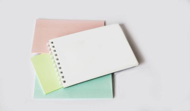 Beyaz arkaplanda, çok renkli çıkartmalar ve yazmak için boş bir not defteri