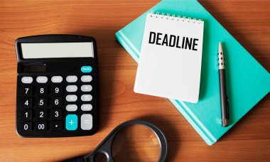 DeadLINE - bir defter üzerinde metin, günlük bir kitabın yanında, bir hesap makinesi ve ahşap bir masanın üzerinde bir büyüteç. Kavramsal iş görüntüsü
