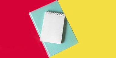 On a red and yellow background is a green diary and a notebook for writing down something