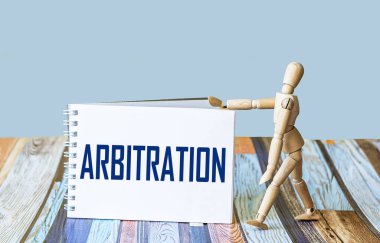 Tahkim kelimesi bir deftere, arka planda tahta bir bebeğin yanına yazılır..