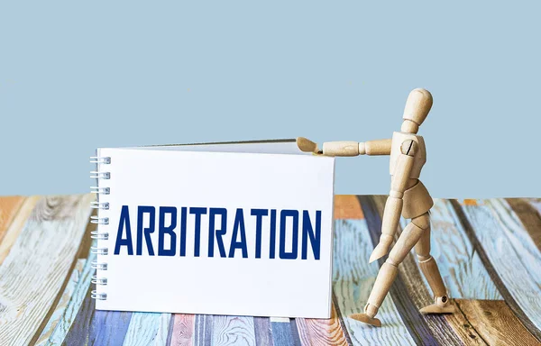 Tahkim kelimesi bir deftere, arka planda tahta bir bebeğin yanına yazılır..