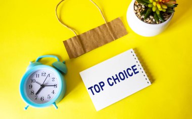 Zirvede CHOICE sarı zemin üzerine küçük bir not defterine alarm saati, kaktüs ve yazılacak bir fiyat etiketi ile yazı yazdı..