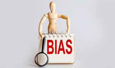 Tahta adam elinde beyaz not defteriyle BIAS metniyle ortaya çıkıyor.
