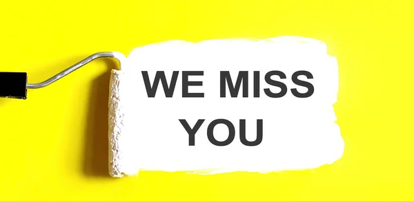 WE MISS YOU One open can of paint with white brush on it on yellow background.