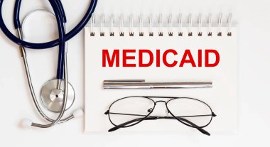 Stetoskop, gözlük ve kalemle beyaz arkaplanda bir MEDICAID